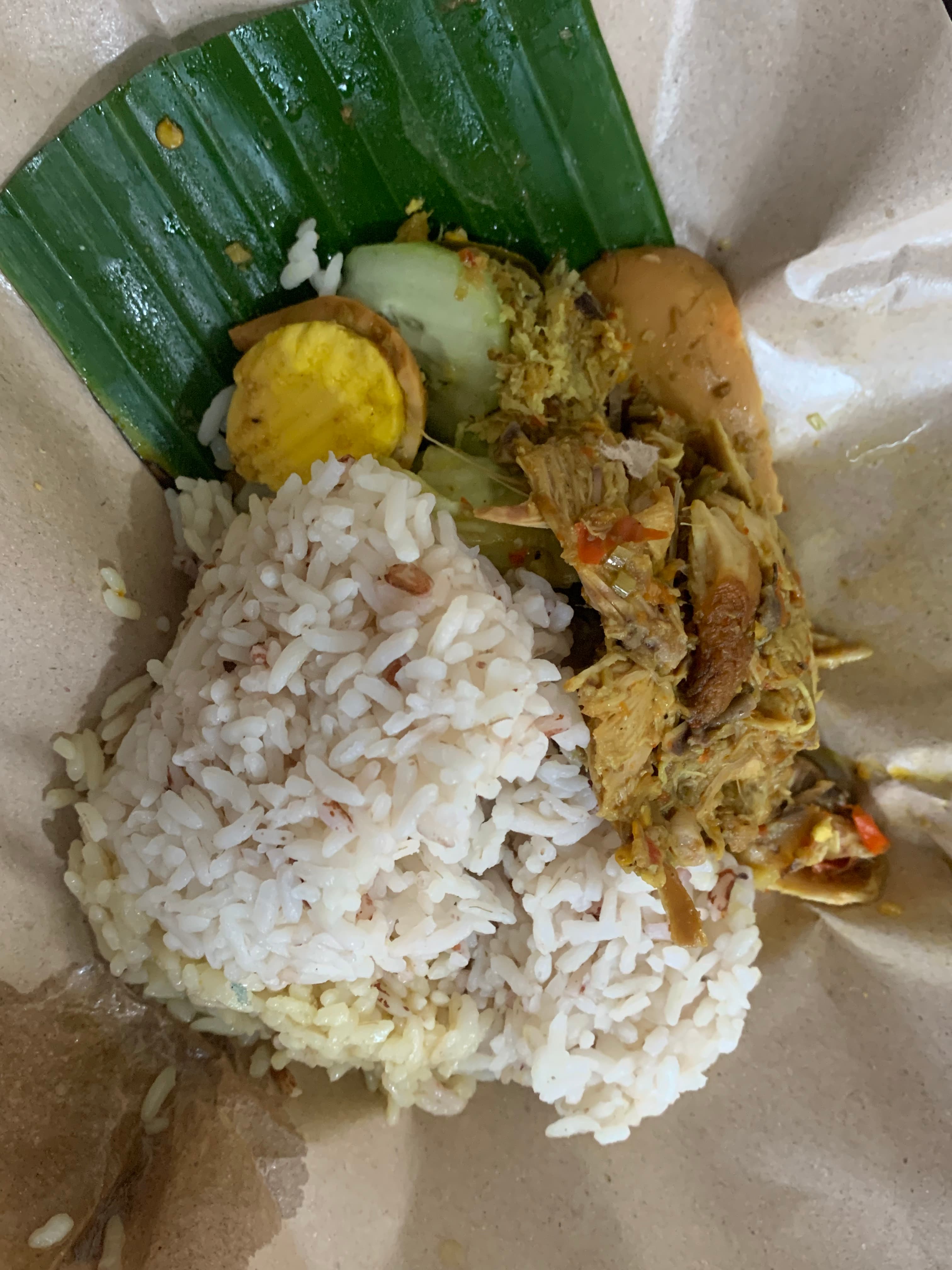 Nasi bungkus daun pisang dengan suwiran Ayam Betutu berbumbu kuning, telur pindang, dan acar timun