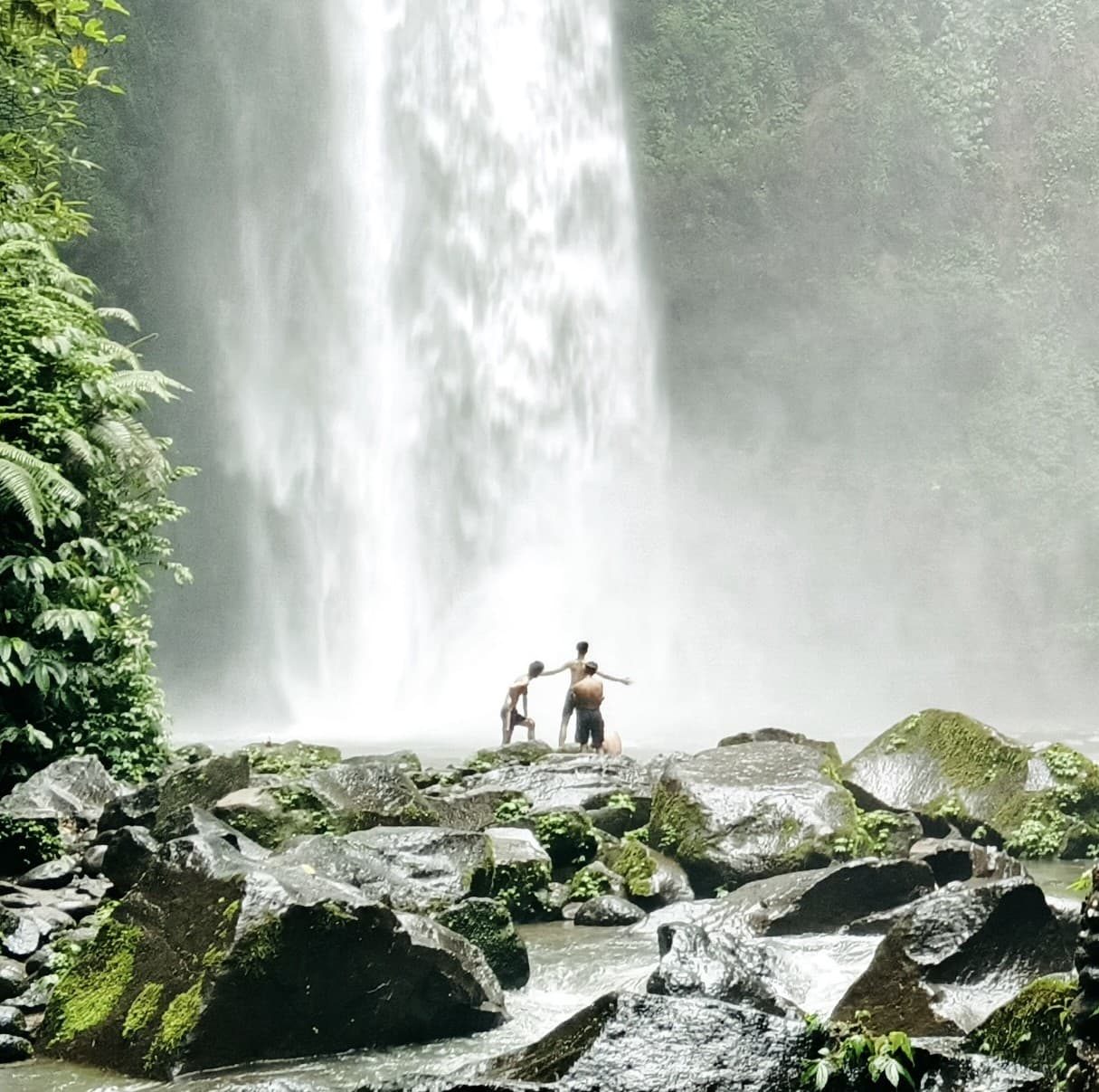 Air Terjun Nungnung yang mengalir deras di antara tebing hijau Pelaga